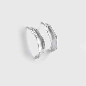 Silver Flame lily petal earrings on soft grey background