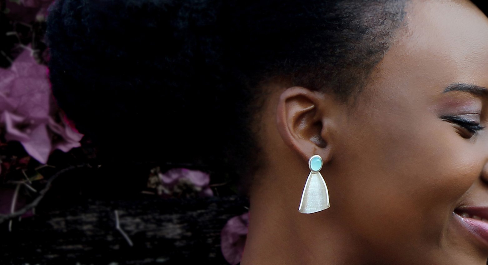 Lady with afro hair and large silver earrings with gemstone