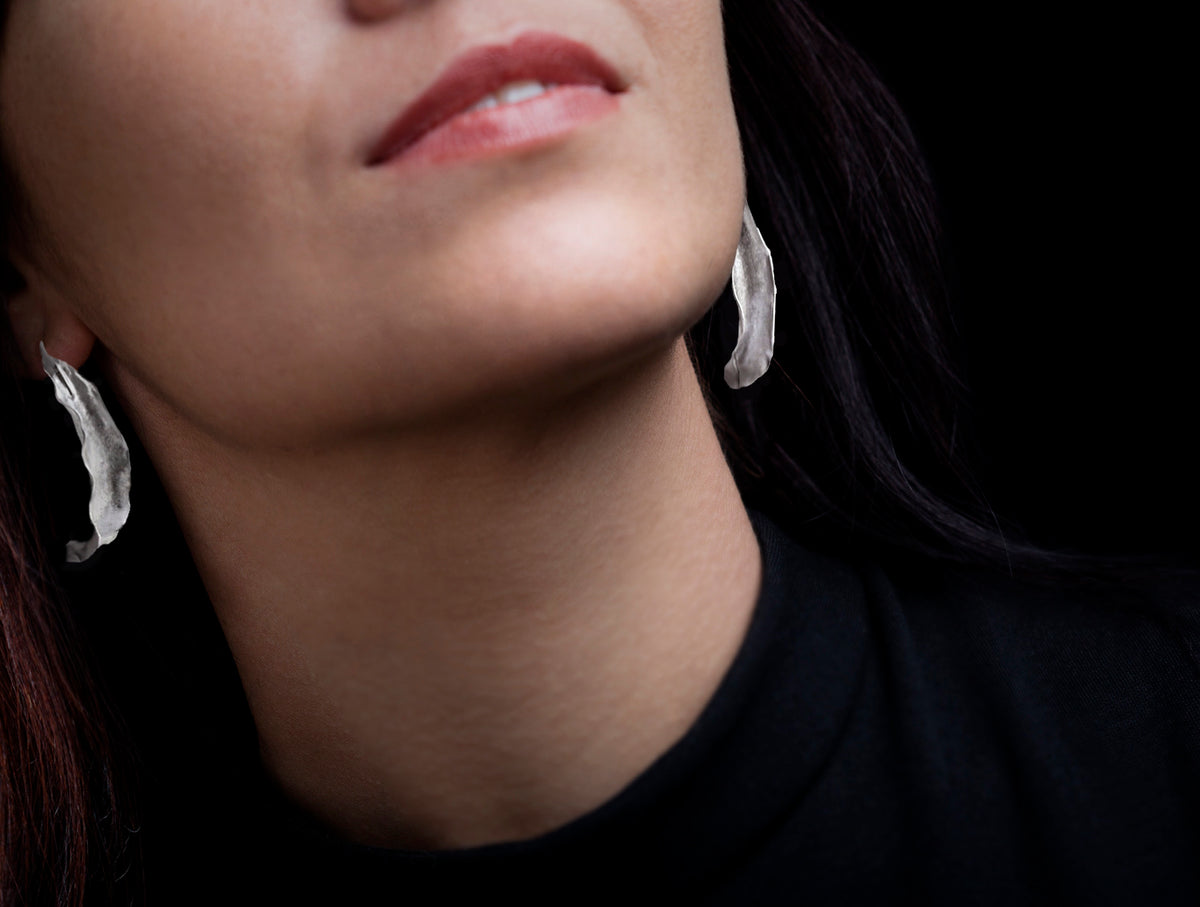 Woman wearing silver flame lily earring black background