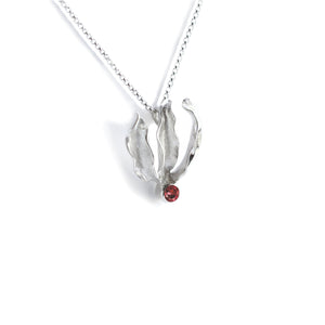 Silver flame lily pendant with red garnet gemstone on chain. White background