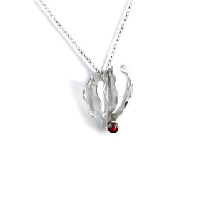 Silver flame lily pendant with red garnet gemstone on chain. White background