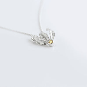 Silver flame lily pendant with citrine gemstone on chain. White background