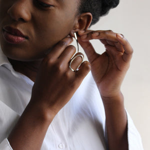 Model Wearing oval ring and putting on earrings