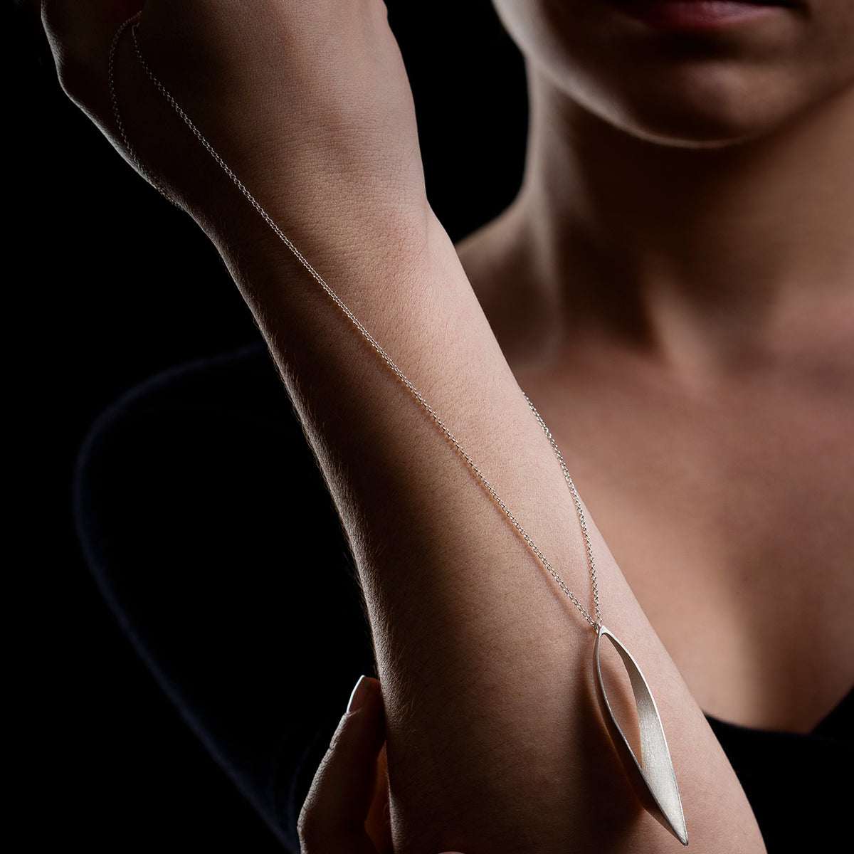 Woman holding a sliver chain against one arm