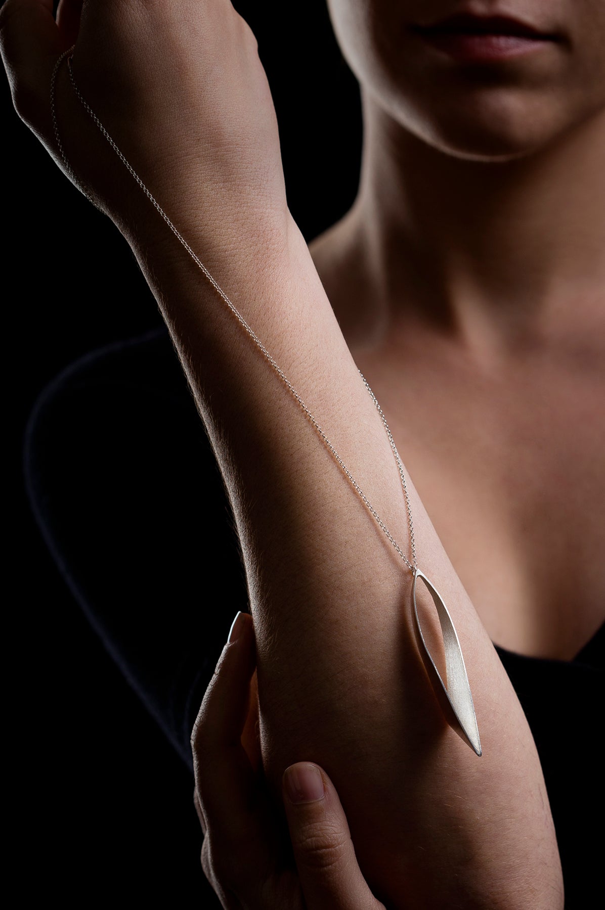 Woman holding a sliver chain against one arm
