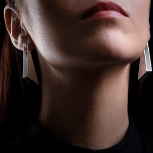 Silver rectangle earrings on model with a black background