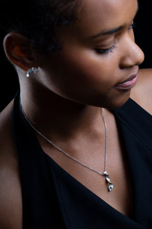 Silver Msasa Studs and chain worn by a woman. Black background