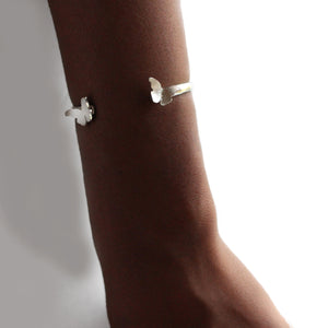 Silver butterfly bangle on a wrist 