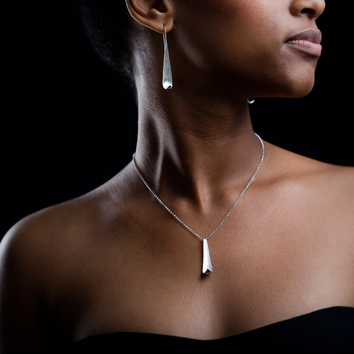 Model wearing Poised Chain and poised studs. Black background