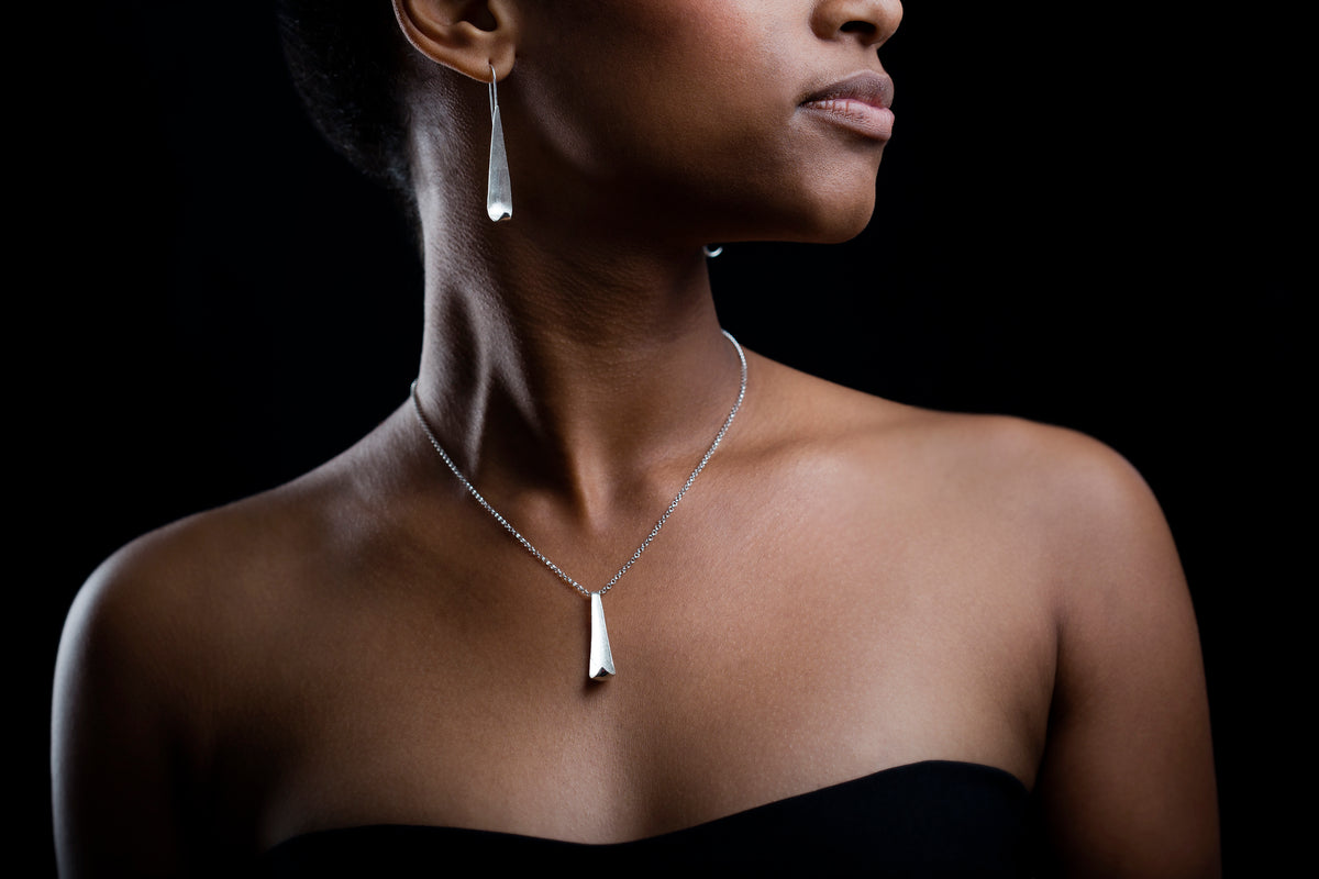 Model wearing Poised Chain and poised studs. Black background