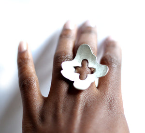 Silver statement ring on a hand against a white background