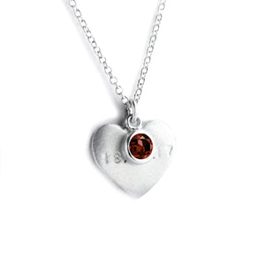 Silver heart on chain with engraved date and red garnet on top