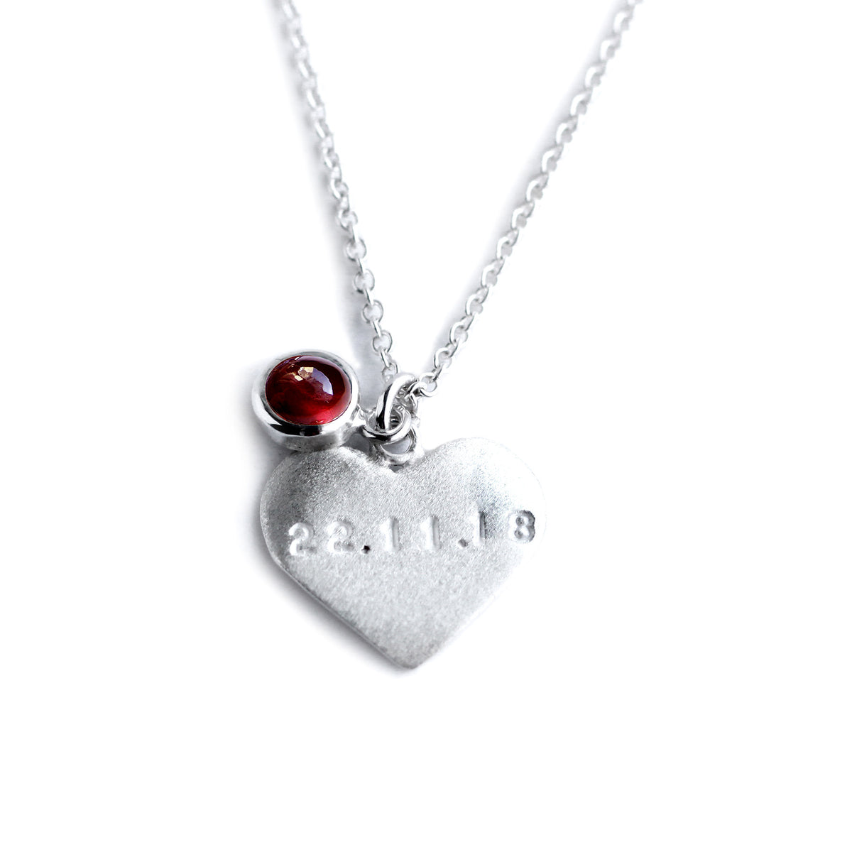 Silver heart on chain with engraved date and red garnet on top